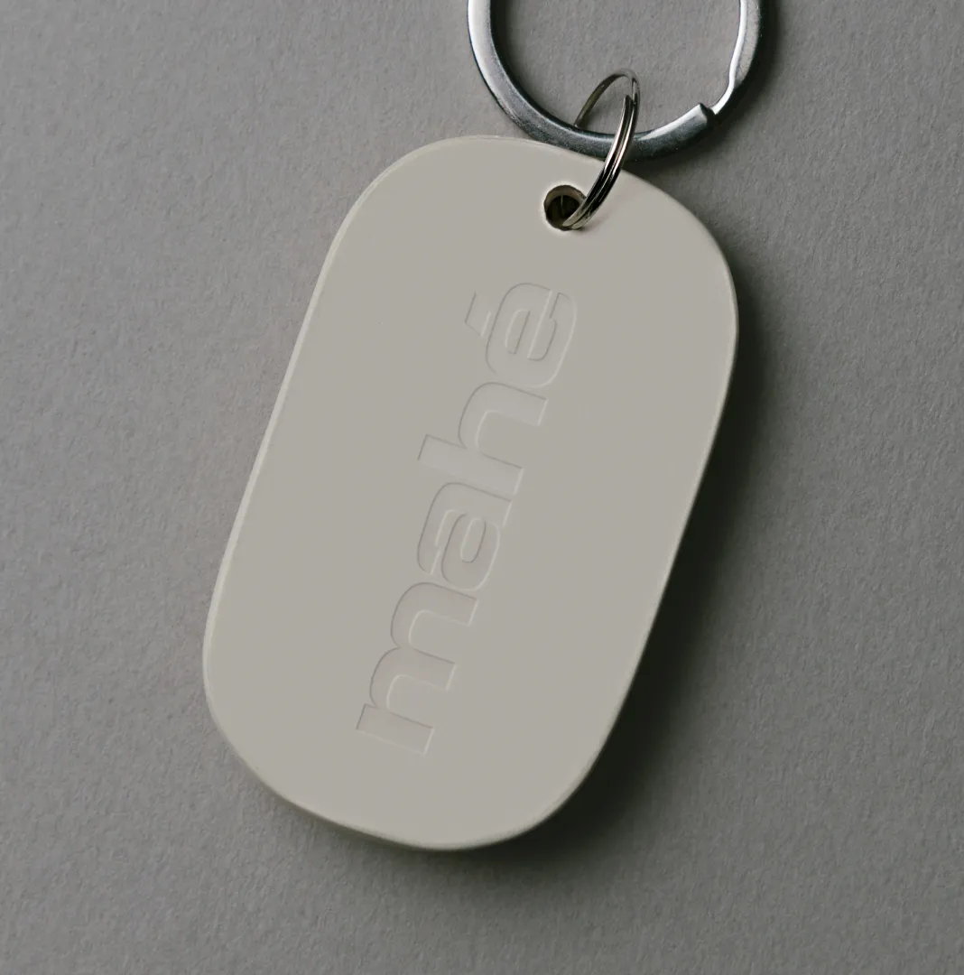 Close-up of an embossed mahé keychain tag on a grey surface