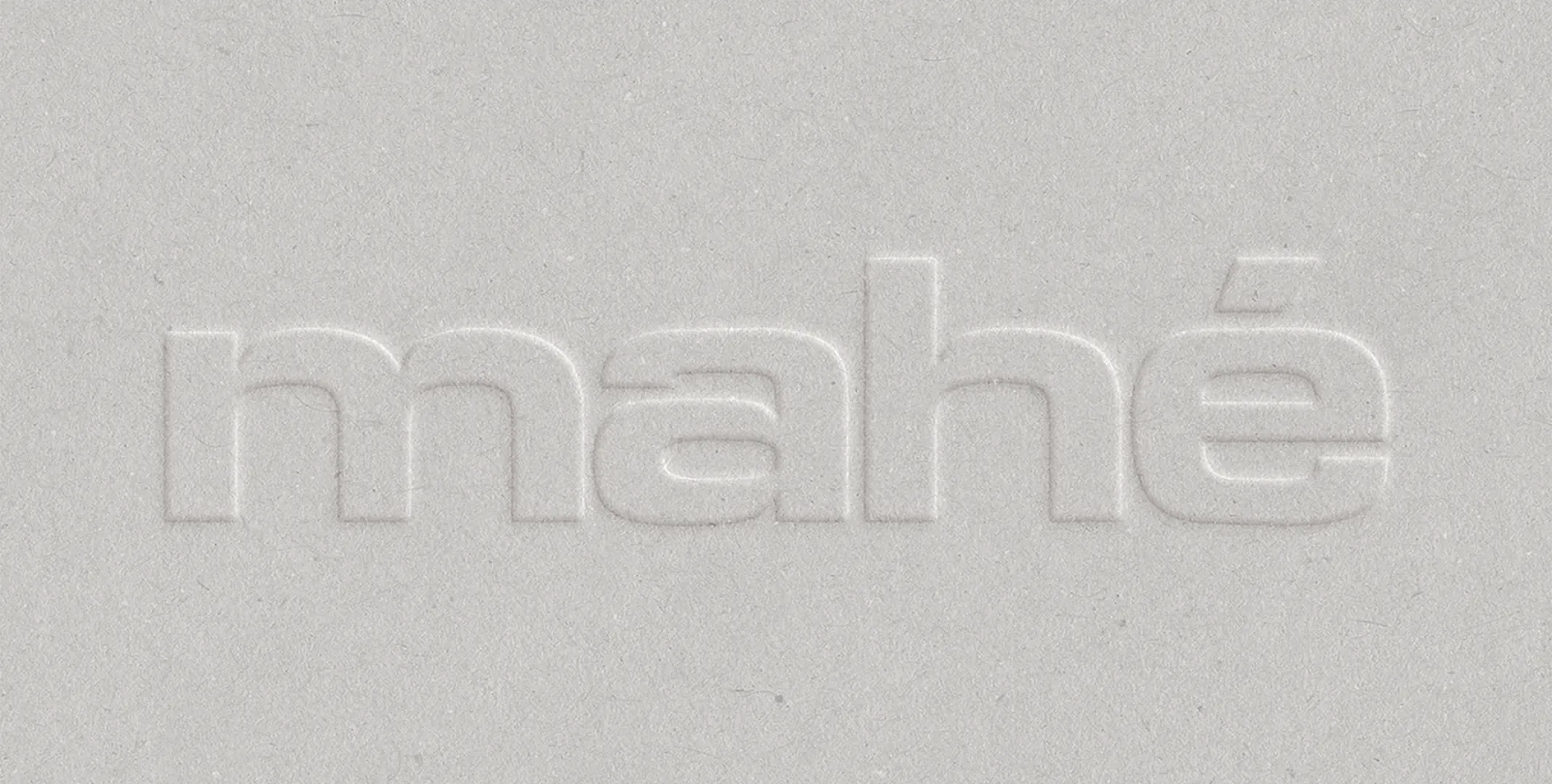 The mahé wordmark blind-embossed on textured off-white paper