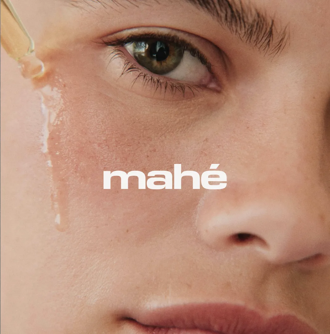 A dropper applying serum to a model's cheek with the mahé logo overlaid